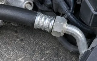 Oily residue on an air-conditioning hose fitting beside the engine