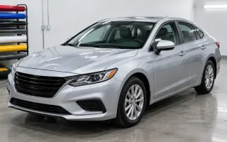 Clean sedan in a wrap shop bay with vinyl rolls and tools on a cart