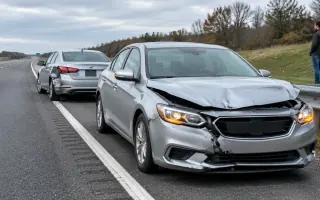 Two cars on a highway shoulder after a collision, a leased sedan with front-end damage