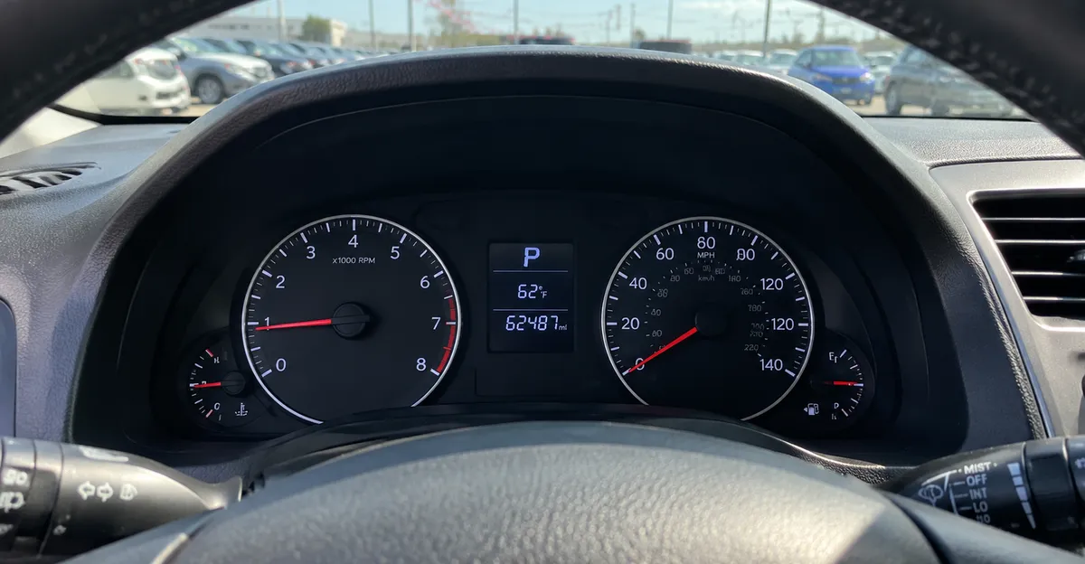 Dashboard odometer and instrument cluster in a used sedan parked on a dealership lot