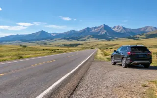 Montana open road with a parked passenger car near foothills