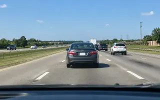 Driver view of a U.S. highway lane with a sedan ahead losing speed in traffic